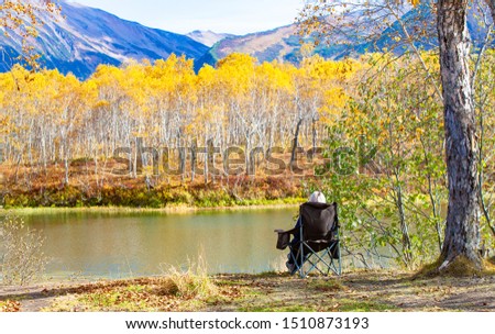 woman in chair for camping, admiring the lake and mountains