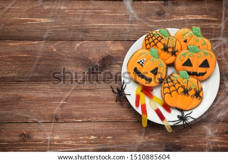 Halloween gingerbread cookies with spiders in plate on brown wooden table