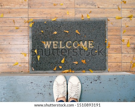 Top view selfie of feet in white sneakers shoes on floor background with welcome mat Royalty-Free Stock Photo #1510893191
