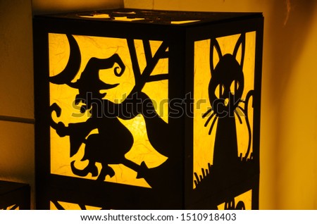Halloween decoration. Silhouette of witch and cat on yellow light