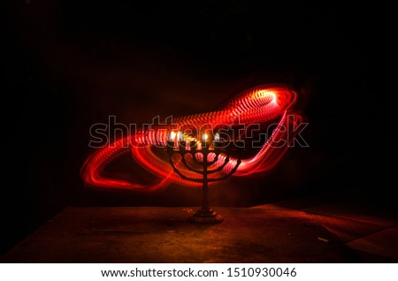 Low key image of jewish holiday Hanukkah background with menorah (traditional candelabra) on dark toned foggy background