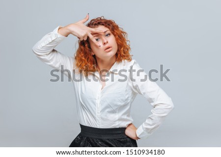 A red-haired girl in a white shirt shows two fingers