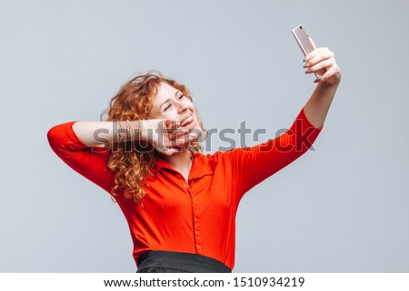 girl takes a selfie on the phone on a light gray background