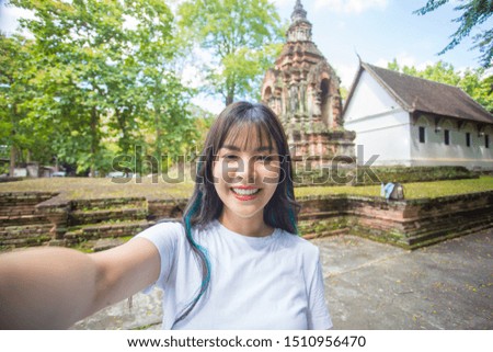 Close-up portrait of Beautiful Asian women walking to old temples and taking pictures of themselves via online media . She is a beautiful smile. Have fun and have clean teeth.