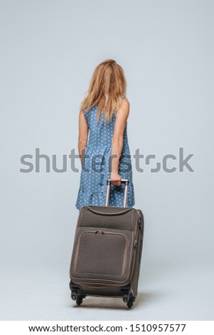 Tourist girl with a suitcase, back view