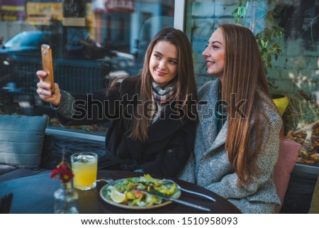 two pretty woman met in cafe taking selfie autumn season