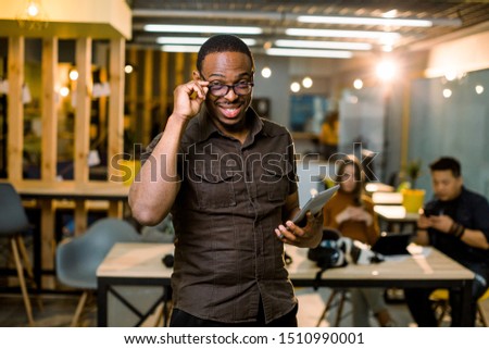selective focus of african american man in casual wear holding digital tablet and colleagues at workplace in modern creative office.