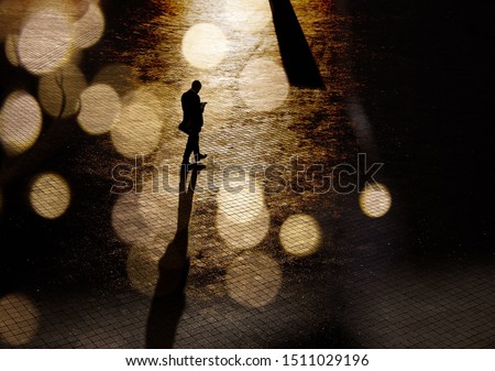 Silhouette of a man in a business suit on the square in abstract bokeh. Stranger, anonymous, spy. Dark photo of a man with shadows in a low key. Royalty-Free Stock Photo #1511029196
