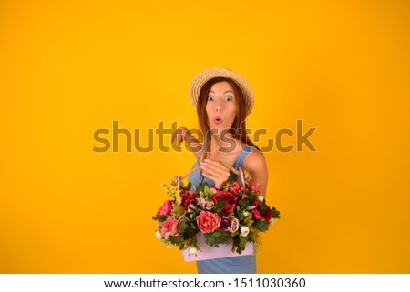 surprised woman in a straw hat with flowers shows a free place on a yellow background