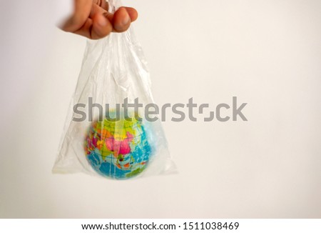 Woman's hand holds the earth in a plastic bag. In the blank for social advertising there is a place for the inscription,The concept of pollution by plastic debris, The Environment concept.