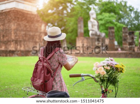 woman tourist enjoy riding local bicycle to see the historic park of Thailand, exciting look at map guide to explore the wonderful place of sightseeing
