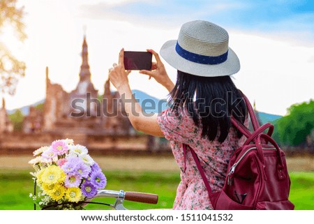 woman tourist enjoy riding vintage bicycle to see the historic park of Thailand, exciting taking photo to the wonderful place of sightseeing
