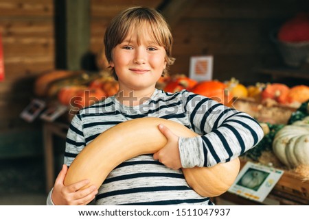 Adorable little boy choosing halloween pumpkin on farm market