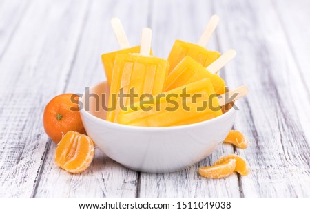 Portion of fresh homemade Tangerine Popsicles (close-up shot; selective focus) on a vintage background