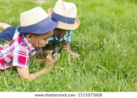 Two boys with magnifying glass outdoors.The concept of friendship of children, brothers, nature research, search and discovery, science and knowledge in biology and botany. Asian children. Image. Royalty-Free Stock Photo #1511073608