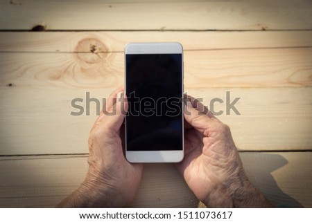 Hands of an elderly man holding and using a phone. The concept of teaching new technologies to older people, communication with the older generation. Image. Royalty-Free Stock Photo #1511073617