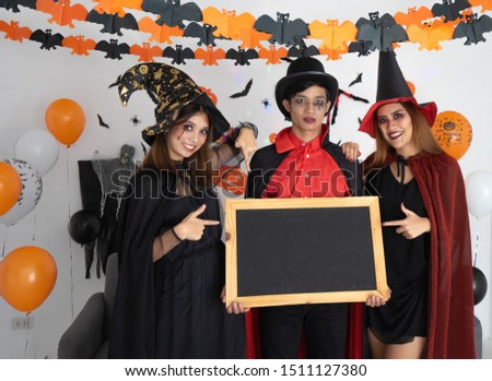 Happy halloween vivid young party friends women and men in costumes makeup on a celebration of Halloween. they are holding Chalk rubbed out on blackboard for a background. texture for add text or grap