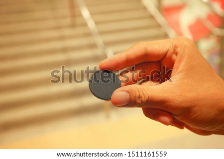 Man holding small round black plastic token coin, math counter or game chip  Royalty-Free Stock Photo #1511161559