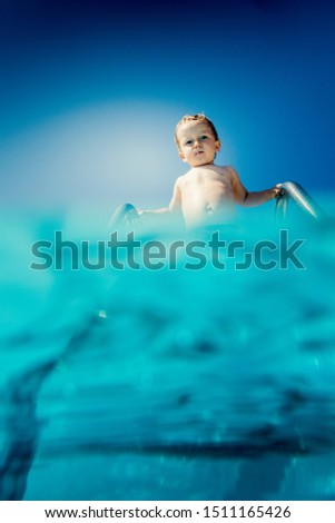 Low angle view of baby boy standing on ladder of swimming pool, Crete, Greece