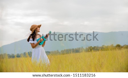 Happy Portrait young asian woman playing  ukulele guitar on   autumn meadow field , lifestyle healthy  travel  concept , banner for text