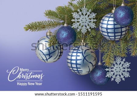 fir branches with Christmas silver balls and snowflakes on a blue background