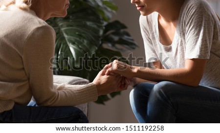 Close up side view of elderly mother and grownup daughter sit at home talk giving advice, loving senior mom and adult offspring child hold hands having intimate close moment, show support and empathy Royalty-Free Stock Photo #1511192258