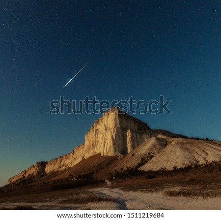 Night star sky and meteor over white rock