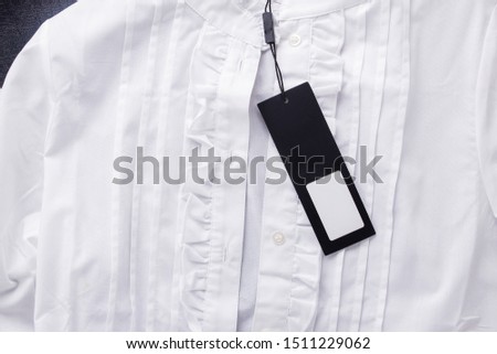 White blouse with a label. Black label for the inscription.