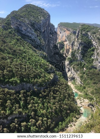 High angle landscape view of the Verdon turquoise water river in the middle of mountains, rocks, cliffs, tress, forest and wild nature, sun shining in spring, Alps, Alpes de Haute Provence, France.