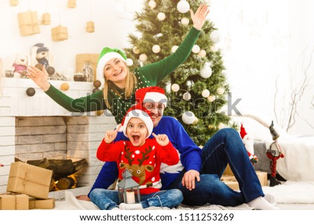 The charming family sitting near Christmas Tree
