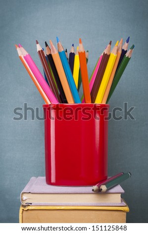 books penholder and colorful pencils in front of green chalkboard Royalty-Free Stock Photo #151125848