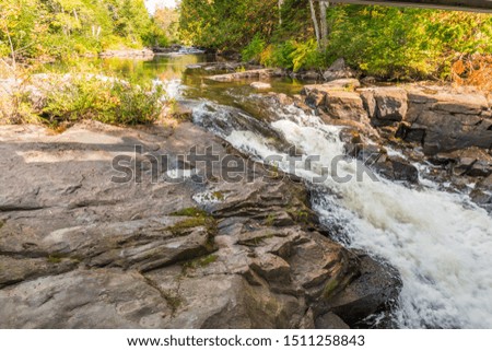 Scenic early fall picture of waterfalls rapids featuring clear river water, brown rocks, river stream and habitat