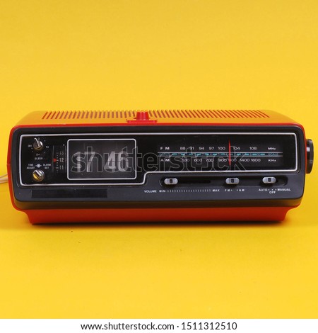 Vintage electronic alarm clock with flip clock. Red retro digital radio alarm clock. Antique. Retro design from 60s 70s home interior. Bright yellow color. FM alarm clock. Royalty-Free Stock Photo #1511312510