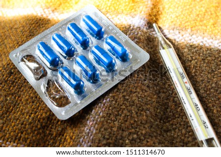 Medication and thermometer on a blanket