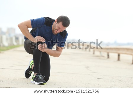 Painful jogger complaining suffering knee ache after sport on a concrete way Royalty-Free Stock Photo #1511321756
