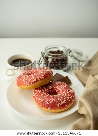 Donuts with red icing and coffee.