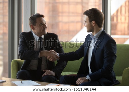 Smiling businessmen in suits handshaking, celebrating contract signing, making partnership agreement, commercial deal, successful negotiate, executive shaking hand of business partner, acquaintance