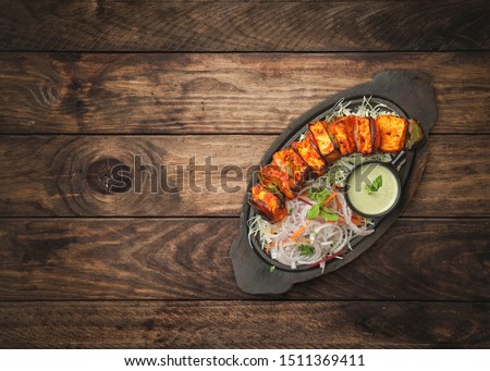 paneer tikka, Tikka paneer served as a starter in wooden sizzler dish on wooden background Royalty-Free Stock Photo #1511369411