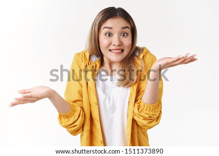 Yikes sorry not knew. Awkward cheerful blond asian woman shrugging hands spread sideways unaware questioned perplexed answer clench teeth uncertain expression clueless say, white background Royalty-Free Stock Photo #1511373890