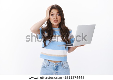 Oops my fault. Clumsy cute and silly woman brunette with curly long haircut, hold laptop, say yikes stare camera grab head, making mistake, have slight accident, apologizing white background Royalty-Free Stock Photo #1511376665
