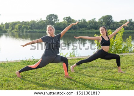 Female friends enjoying relaxing yoga outdoors in the park.