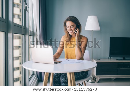 Happy woman chatting with followers from social networks via modern laptop device while calling to friend for talking, positive skilled female booking hotel for summer trip during leisure in home Royalty-Free Stock Photo #1511396270