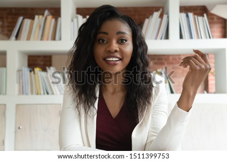 African businesswoman sit indoors looks at camera talking with corporate client discuss common business use virtual communication make video call, skilled coach helps to apprentice distantly concept Royalty-Free Stock Photo #1511399753