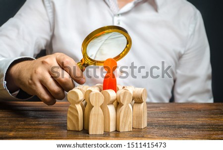 A man is studying the red figure of a man at the head of a crowd. Identify disloyal, repression, dissent. toxic, non-competent worker. Search for the organizer and leader of the protests. Crime. Royalty-Free Stock Photo #1511415473