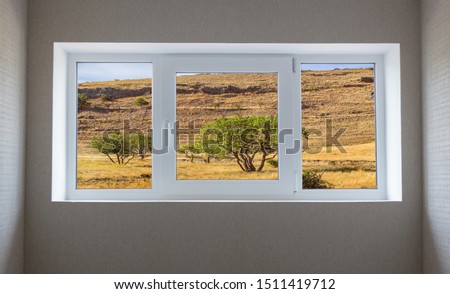 Window view of a beautiful mountain landscape with trees and field