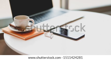 Cropped shot of workplace with laptop computer, smartphone, coffee cup with copy space on white desk 