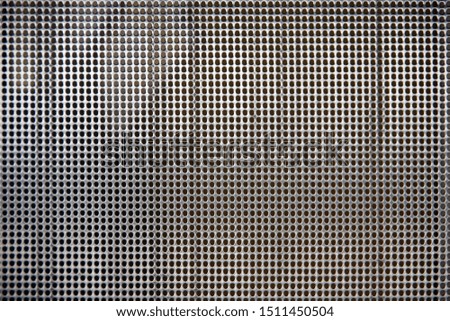 Close-up full frame view of a section of a sheet of chrome steel with a sieve like geometric pattern of round holes as used in air duct outlets