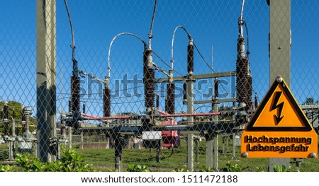 High-voltage switchgear with fence and safety instructions. Sign: Hochspannung - Lebensgefahr, engl. High voltage - Danger to life