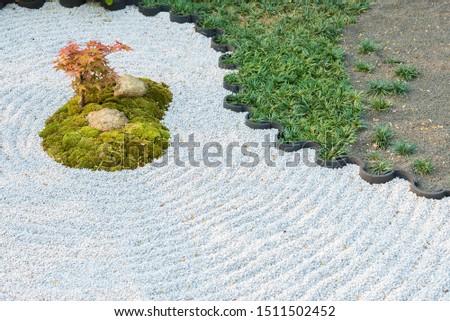 Japanese zen garden with plant, stone in raked sand