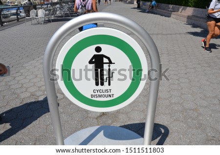 green cyclist dismount sign and cement sidewalk